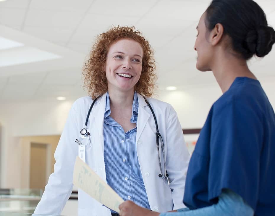Una médica que sonríe hablando con una enfermera