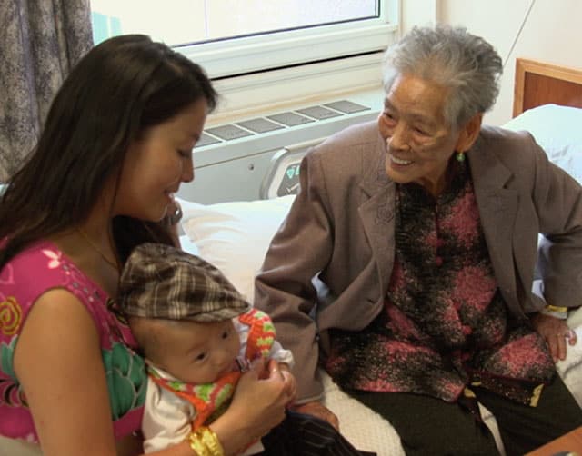 Woman Holding a Child Sits with Elderly Woman