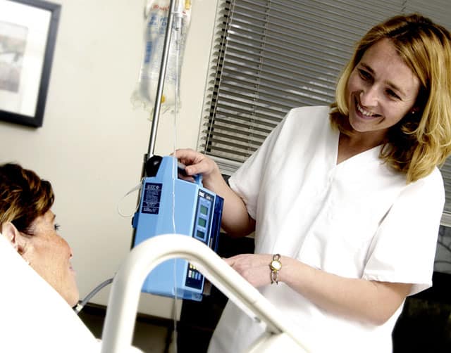 Smiling Nurse Assists Patient in Hospital