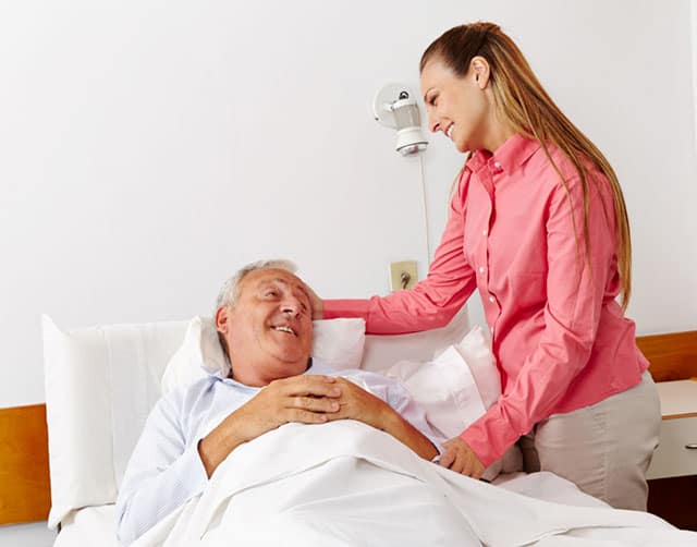 Una mujer conforta a un paciente sonriente en la cama del hospital