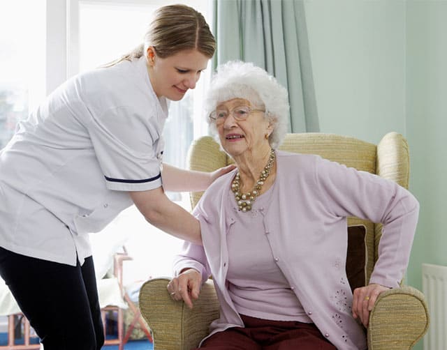 skilled_assisted Caregiver Assists Elderly Woman Out of Chair