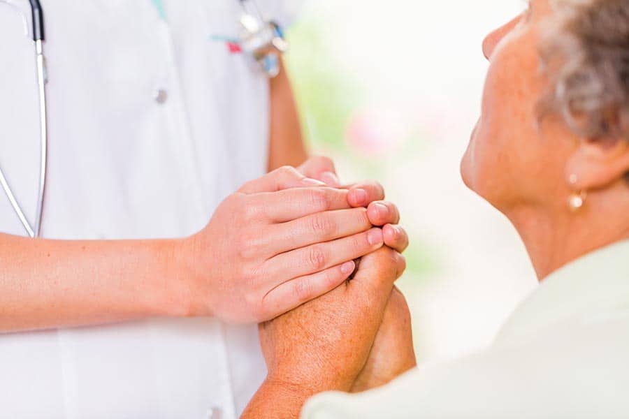 Un enfermero consuela a una paciente tomándole las manos