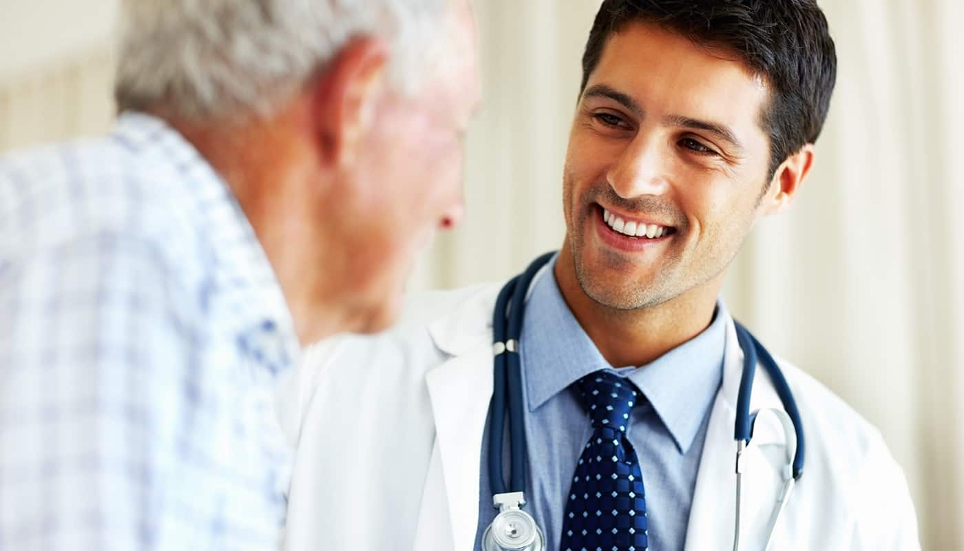 Médico sonriendo y hablando con un paciente mayor