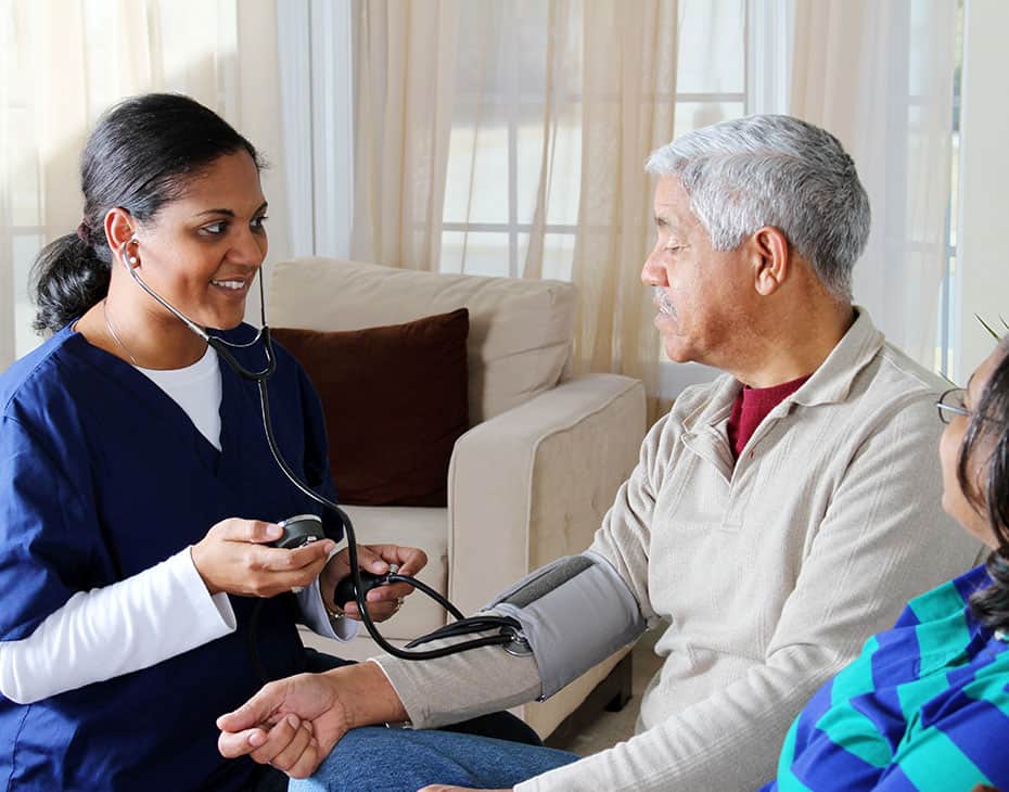 skilled_nursing_care Female Home Caregiver Taking Senior Male's Blood Pressure with His Partner Nearby