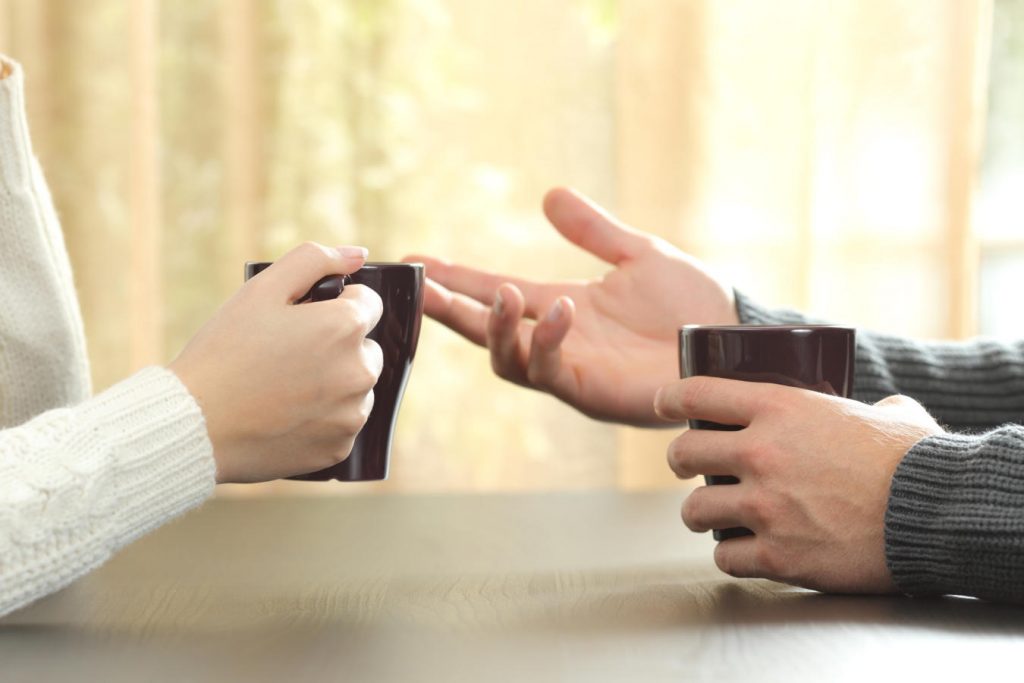 Hands of Two People Holding Coffee Mugs and Talking