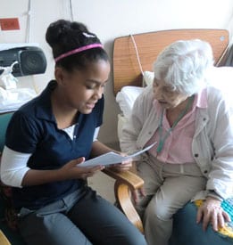 LongTermCare05 Young Female Reads to an Elderly Female Patient