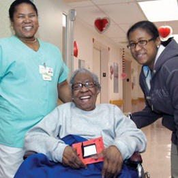 LongTermCare07 Patient in a Wheelchair Smiles with Nurse and Young Woman