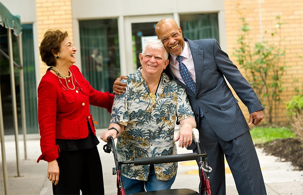 LongTermCare_936x635 MJHS Resident Smiles and Laughs with Two Well Dressed Businesspeople