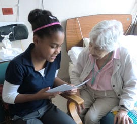 Una joven le lee a una paciente mayor