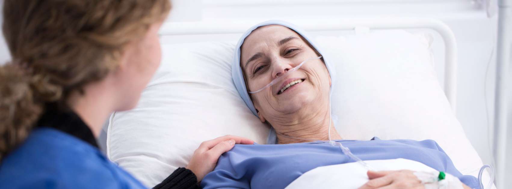 Sick Woman in Bed receiving comfort care from nurse