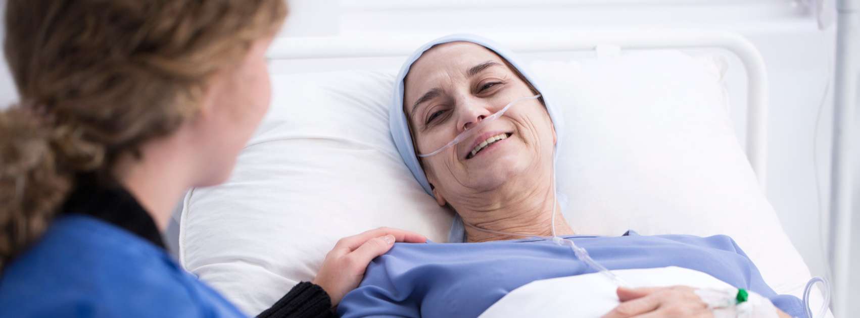 Woman Receives Care Sick Woman in Bed receiving comfort care from nurse