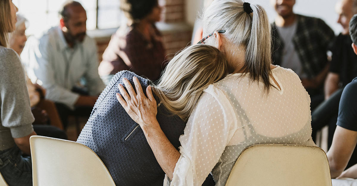 Daughter comforting mother during group therapy session