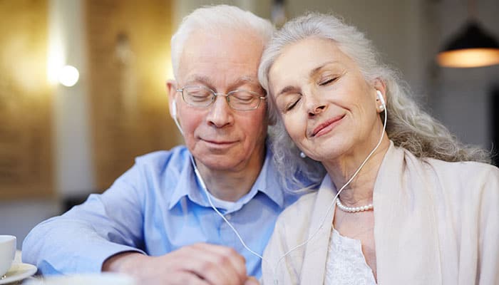 Music-Therapy elderly couple sharing headphones to listen to music