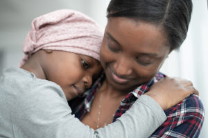iStock-1187487353-1200x800 A child rests their head on their mother's shoulder; the mother looks down at the child and smiles