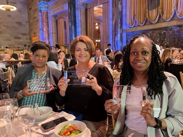 Three women holding up awards at the UHF Awards ceremony